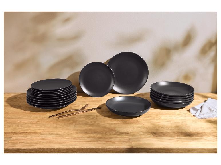 Matzwarte keramische borden met koperen bestek op een houten tafel.