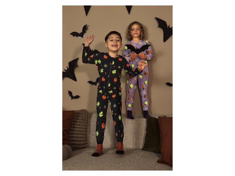Twee kinderen in Kinder Schlafoverall-pyjama's met Halloween-thema springen op een bank.