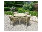 Tuinset met ronde tafel en vier stoelen met kussens op een kiezelpad in een tuin.