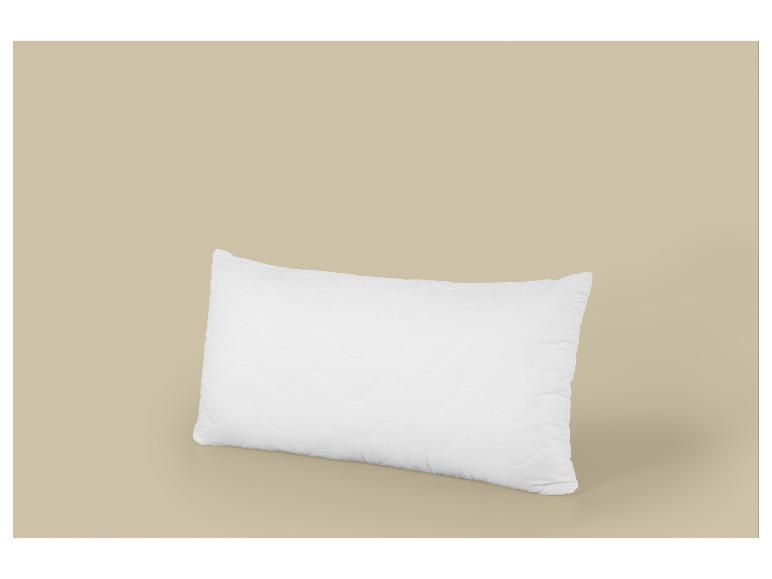 Wit rechthoekig kussen met golvend patroon op een beige achtergrond