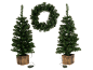 Twee kunstkerstbomen in potten en een kerstkrans, allemaal verlicht.