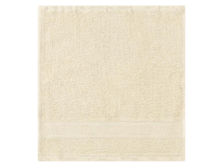 Een crèmekleurige badhanddoek met geborduurde rand.