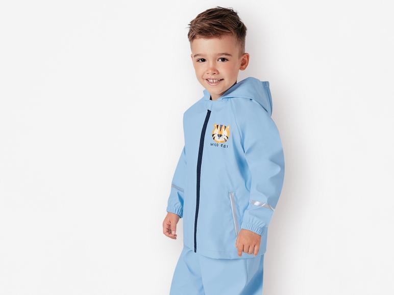 Een jongetje draagt een blauwe regenjas met een tijgerprint.