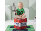 Lachend kind met speelgoedzwaard, zittend op een TNT-blokvormige opbergdoos, op een videogame-thema vloerkleed.