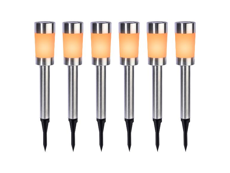 Zes roestvrijstalen solar tuinlampen met oranje licht.