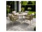Buiten eethoek met ronde tafel en vier stoelen op een terras met tuinplanten.