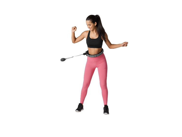 Lachende vrouw met een slimme hoelahoep en roze legging.