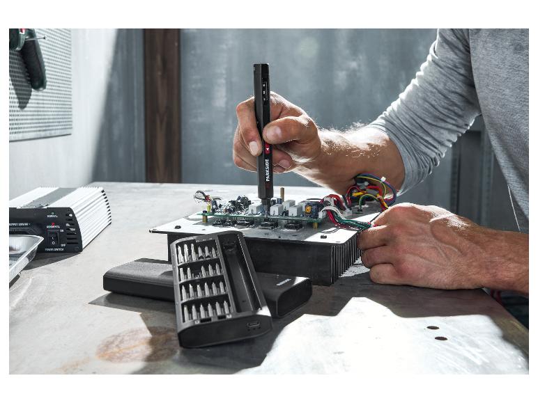 Man repareert elektronica met een precisieschroevendraaierset en omvormer.