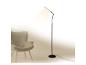 Moderne zwarte vloerlamp verlicht grijze fauteuil in minimalistisch interieur.