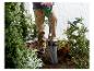 Persoon plant met een tuinspade in een tuin met rozen en struiken.