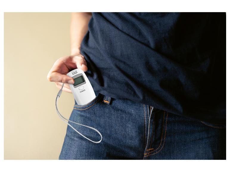 Een persoon haalt een witte alcoholtester uit zijn zak.