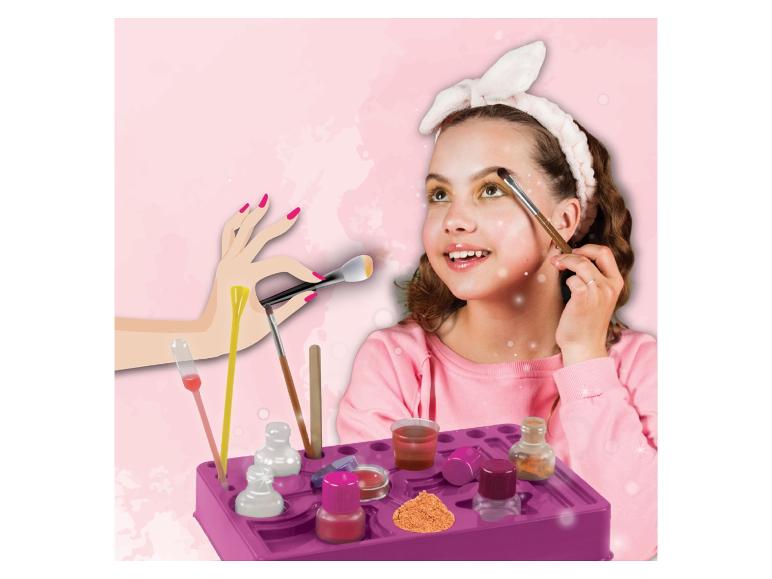 Een meisje doet make-up aan met kwasten en potjes.