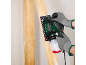 Man met handschoenen gebruikt een elektrische schuurmachine op een houten plank.