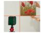 Een laserwaterpas projecteert kruislijnen op een muur, terwijl handen een schilderij met rode bloemen plaatsen.