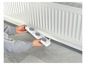 Een persoon houdt een radiatorrooster met drie ventilatieopeningen vast.