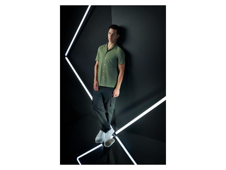 Mannelijk model in een kort mouw overhemd en cargo broek.