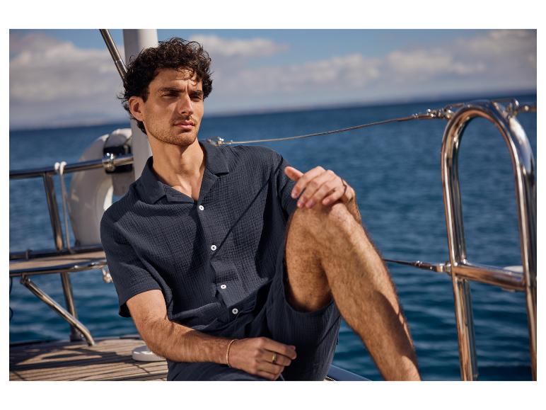 Een man in een donkere overhemd en korte broek op een jacht.