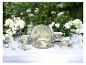 Groen theeservies met bloemen- en vogelpatroon, versierd met witte bloemen op een buitentafel.