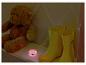 Teddybeer, regenlaarzen en roze nachtlampje op een plank.