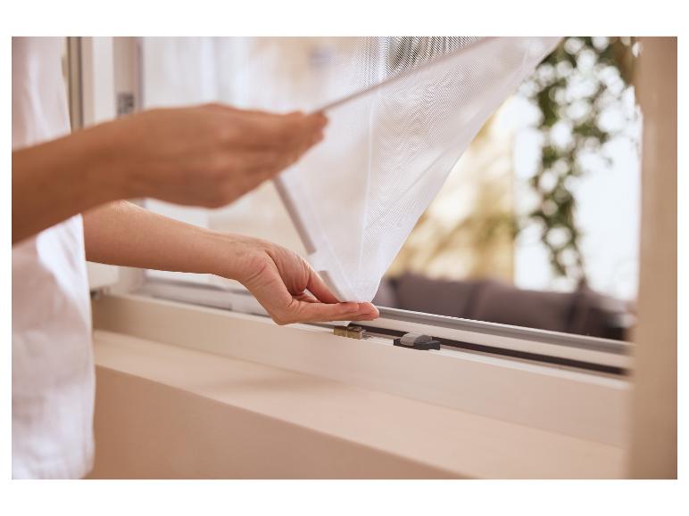 Persoon installeert een wit insectenhor op een raam.