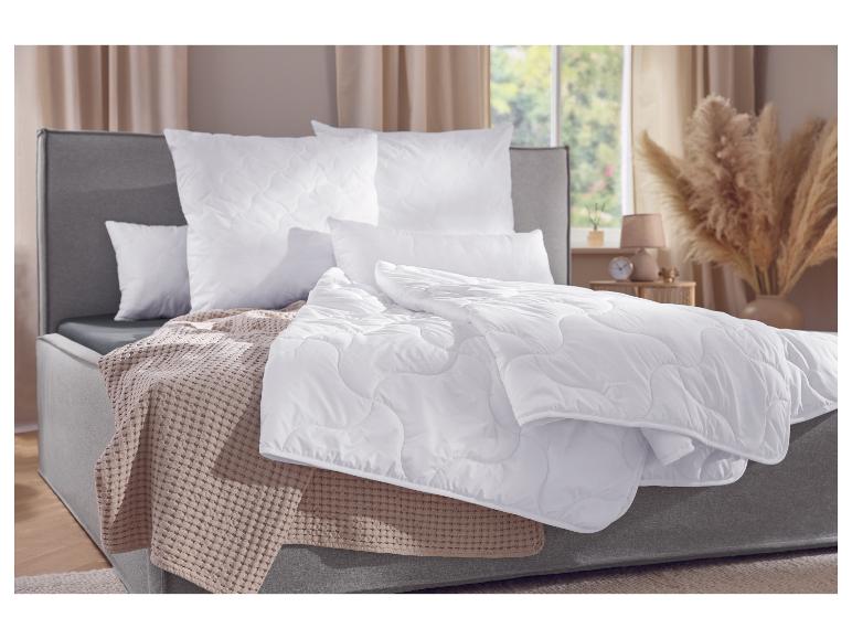 Slaapkamer met grijs bed, witte dekbedden en kussens, en een beige plaid.