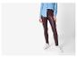 Vrouw in spijkerblouse en bordeauxrode legging met witte sneakers.