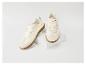 Beige sneakers met roze accenten en bruine rubberen zool op een wit blok.