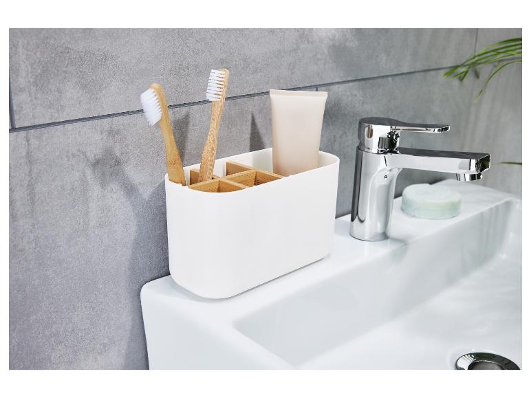 Een witte badkamerorganizer met twee tandenborstels en een tube tandpasta.