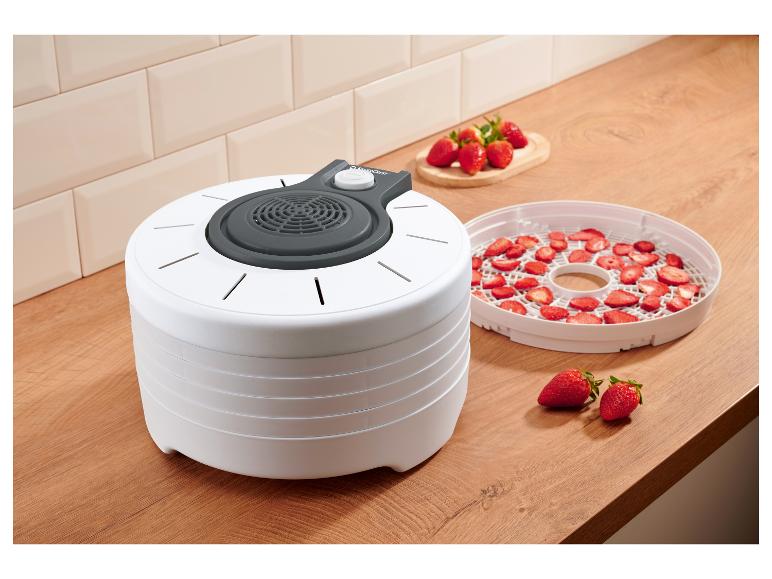 Witte voedseldroger met verse en gedroogde aardbeien in een keuken.