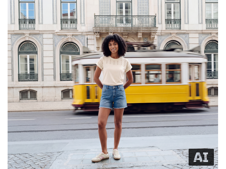 Vrouw in beige opengewerkt T-shirt en denim short voor een gele tram.