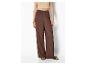 Vrouw in lichte top en bruine wijde broek met sandalen.
