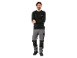 Een man in een zwart shirt met lange mouwen en een grijze werkbroek met kniebeschermers