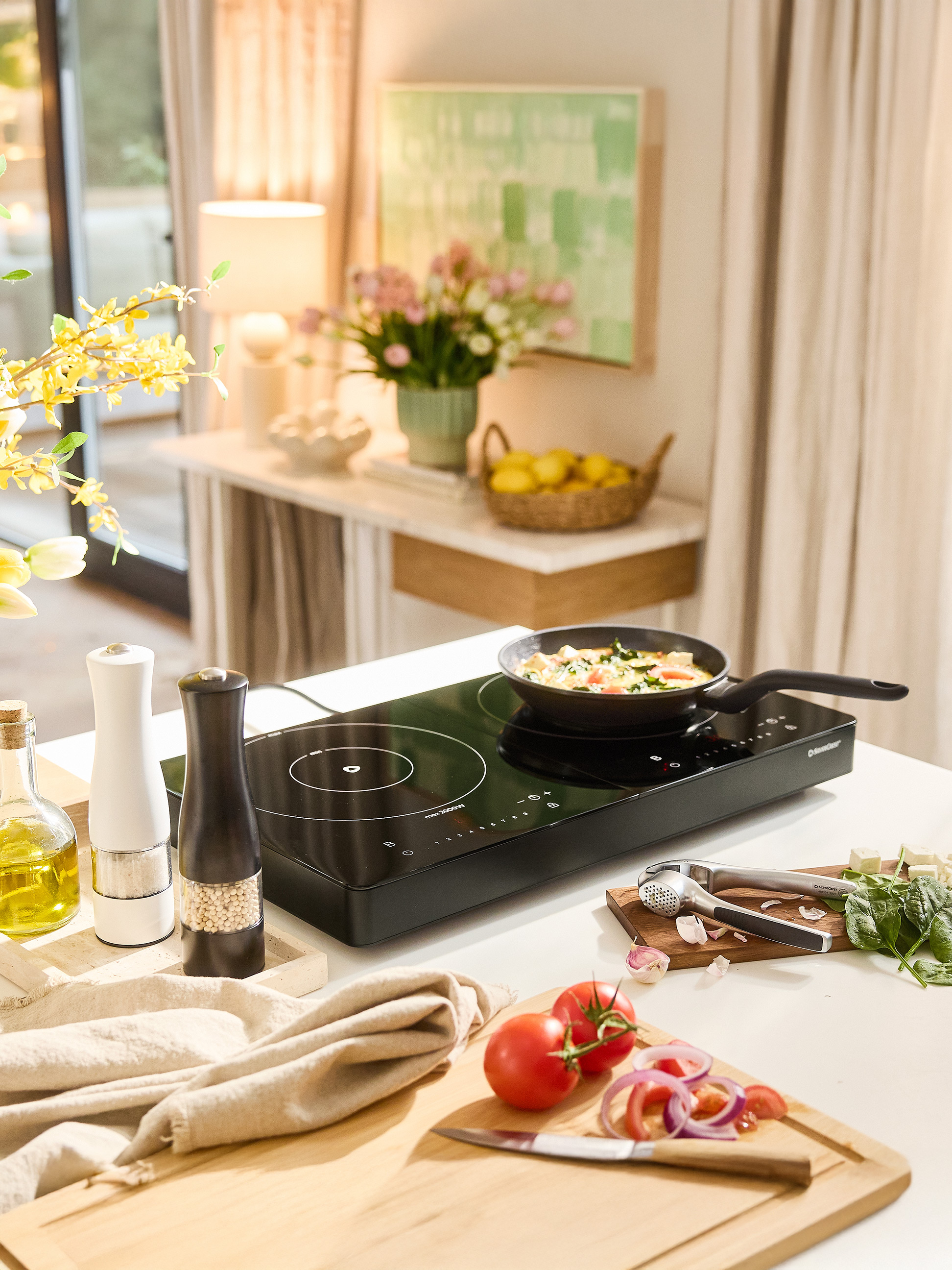 SilverCrest inductiekookplaat met pan, kruiden en verse groenten op een aanrecht.