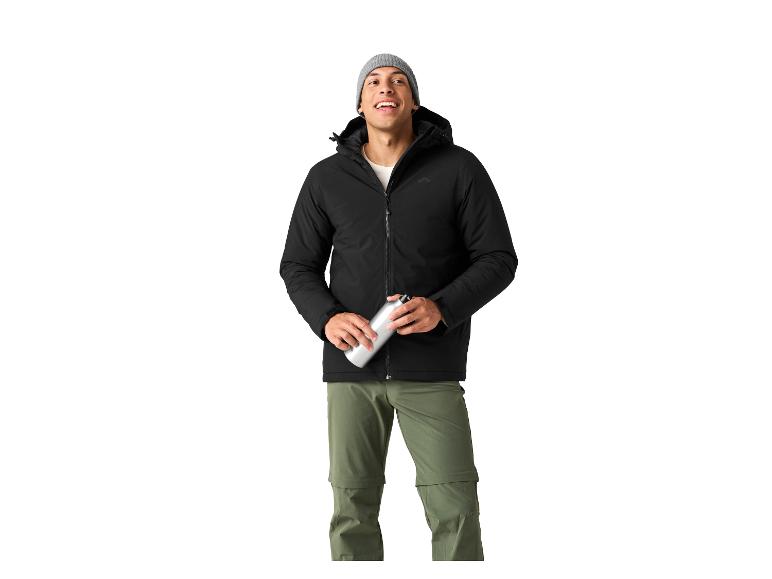 Lachende man in zwarte jas en kaki broek, met een waterfles.