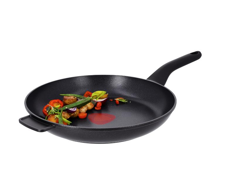 Zwarte koekenpan met geroosterde groenten, waaronder aardappelen, paprika en ui.