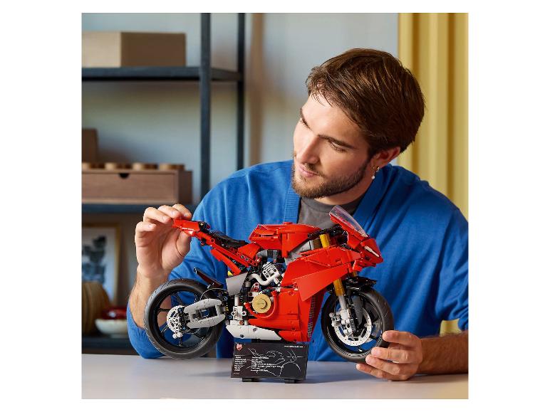 Een man bewondert een rode Ducati Panigale V4 R motorfiets gemaakt van bouwstenen.
