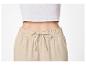 Vrouw in witte geribbelde crop top en beige broek met trekkoord.