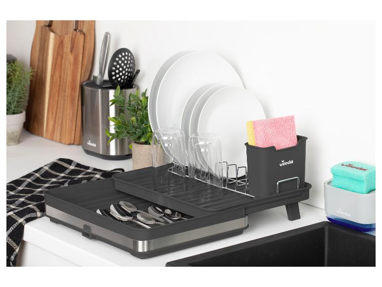 Grijs afdruiprek met vaat, bestek en schoonmaakaccessoires op een aanrecht.