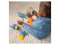 Baby speelt met tekenfilmfiguren en een spiegel op een vloerkleed.
