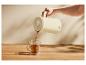 SILVERCREST® thermoskan die thee in een glazen mok schenkt op een houten tafel.