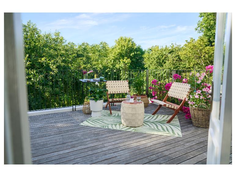 Balkon met houten vloer, twee klapstoelen, een tafel en planten.