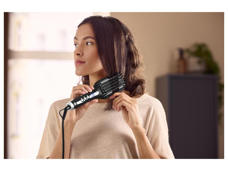 Vrouw die een elektrische stijlborstel gebruikt voor haar haar.