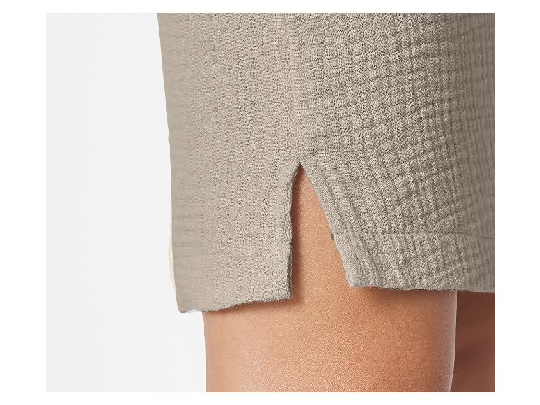 Detail van beige shorts met een split aan de pijp, die huid onthult.