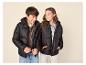 Twee lachende kinderen in zwarte pufferjacks en casual kleding.
