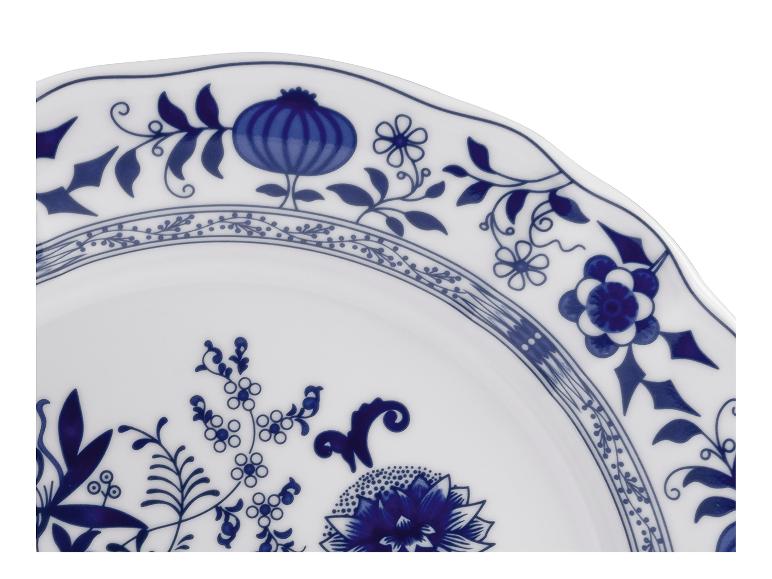Wit bord met blauw bloemmotief en golvende rand.