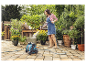 Een vrouw gebuikt een Gardena tuinslang om planten in potten water te geven.
