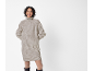 Vrouw in een beige geribbelde coltrui jurk en zwarte laarzen, lachend.