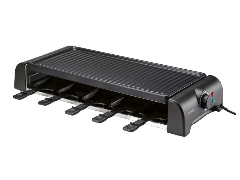 Zwarte raclette grill met zes kleine pannetjes en een geribbeld bovengrilloppervlak.