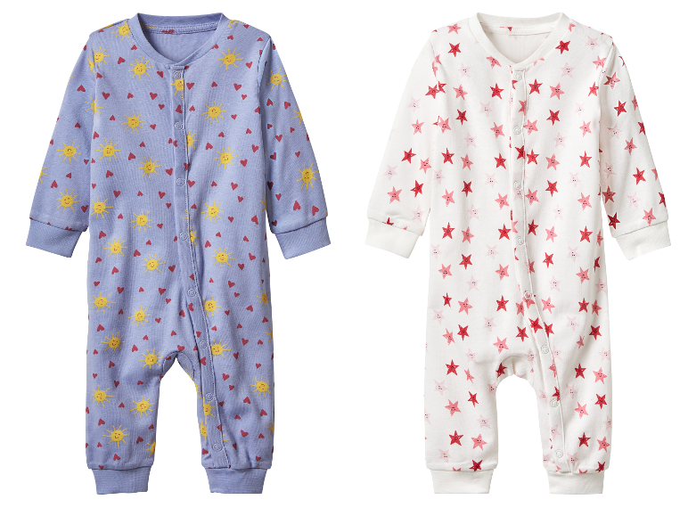 Twee baby-pyjama's, één met zonnetjes en hartjes, de ander met sterretjes.