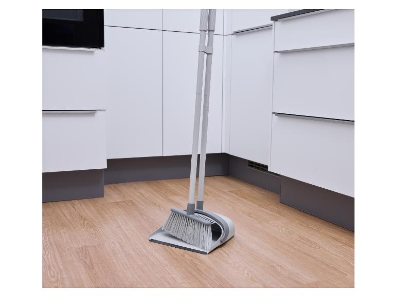 Grijze bezem en stoffer in een moderne keuken met witte kasten.
